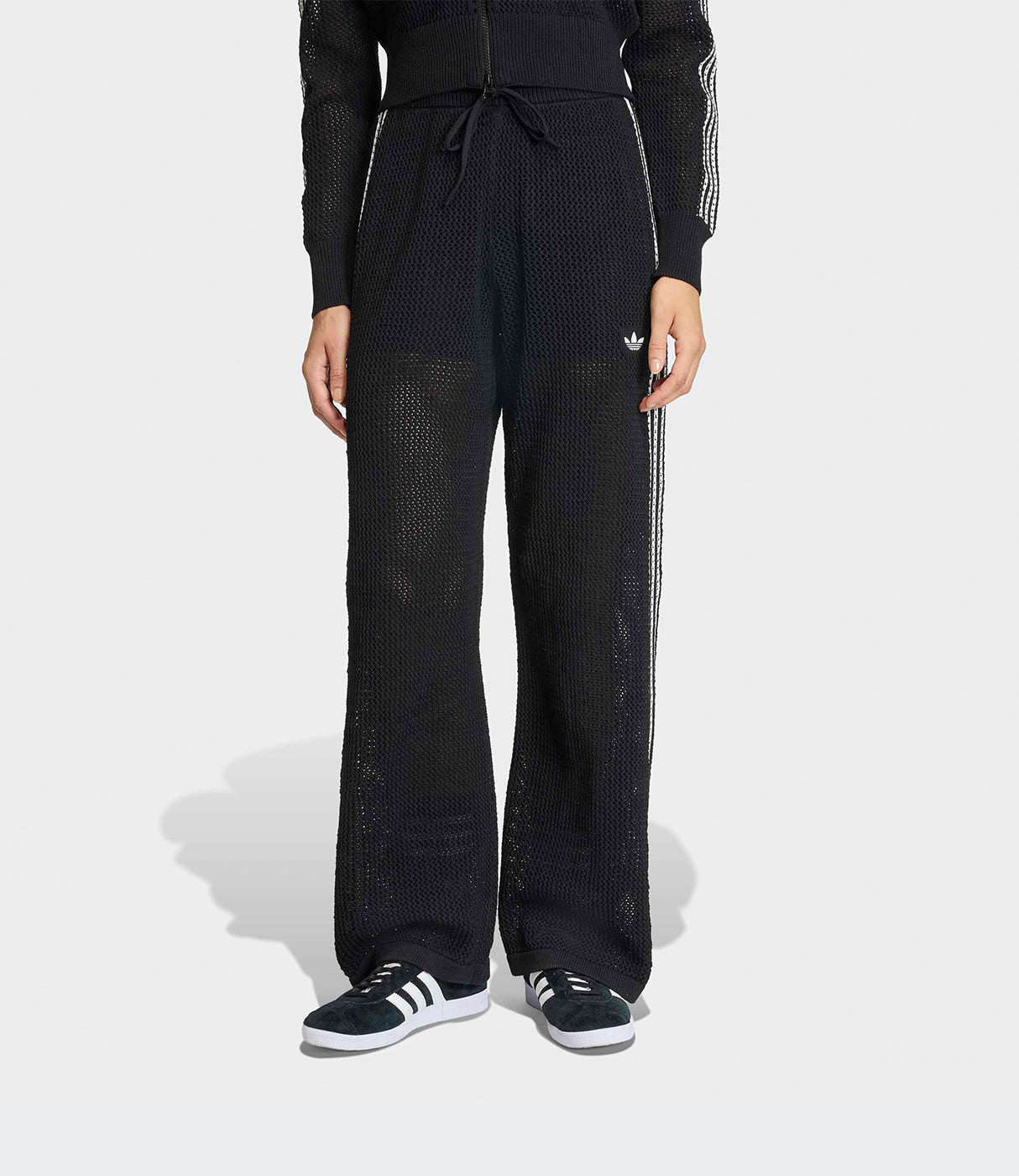 מכנסי טרנינג שחורים בד רשת עם פסי צד ולוגו, נעלי ספורט שחורות, תצוגת דגם