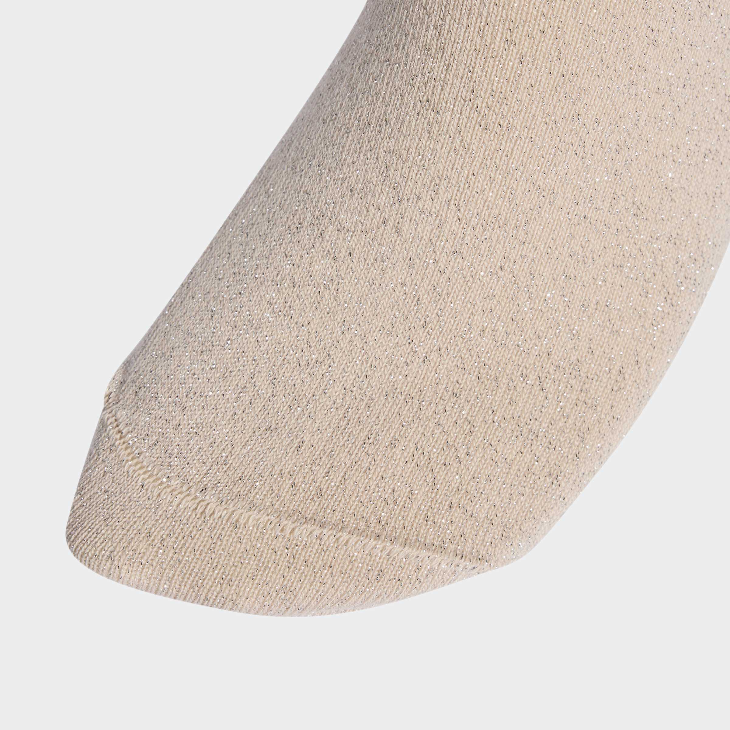 תקריב בד גרב נשים בצבע בז' עם חוטי נצנוץ, רקע אפור בהיר