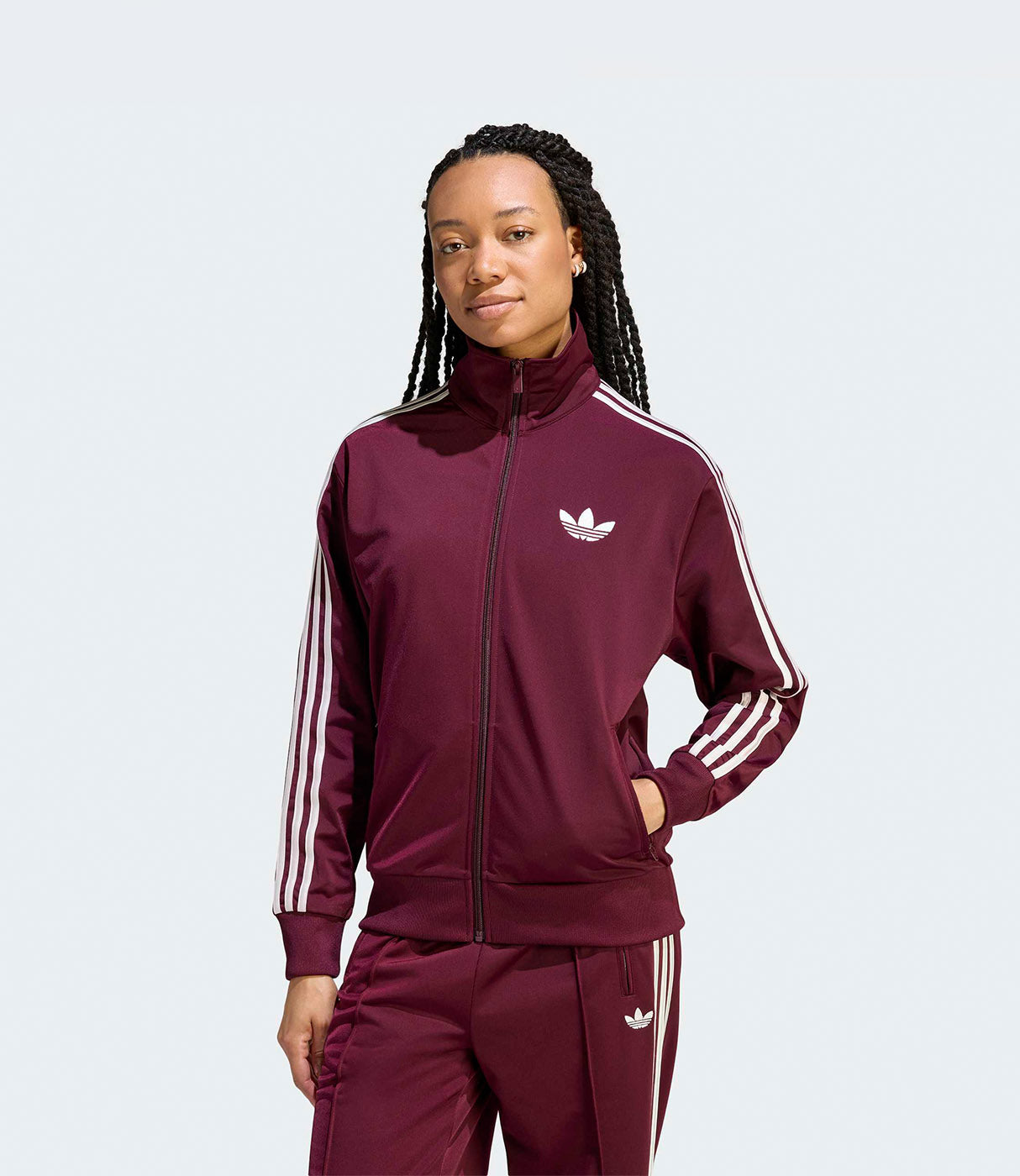 אישה לובשת סט טרנינג בורדו עם פסי צד לבנים ולוגו עליון, רקע פשוט
