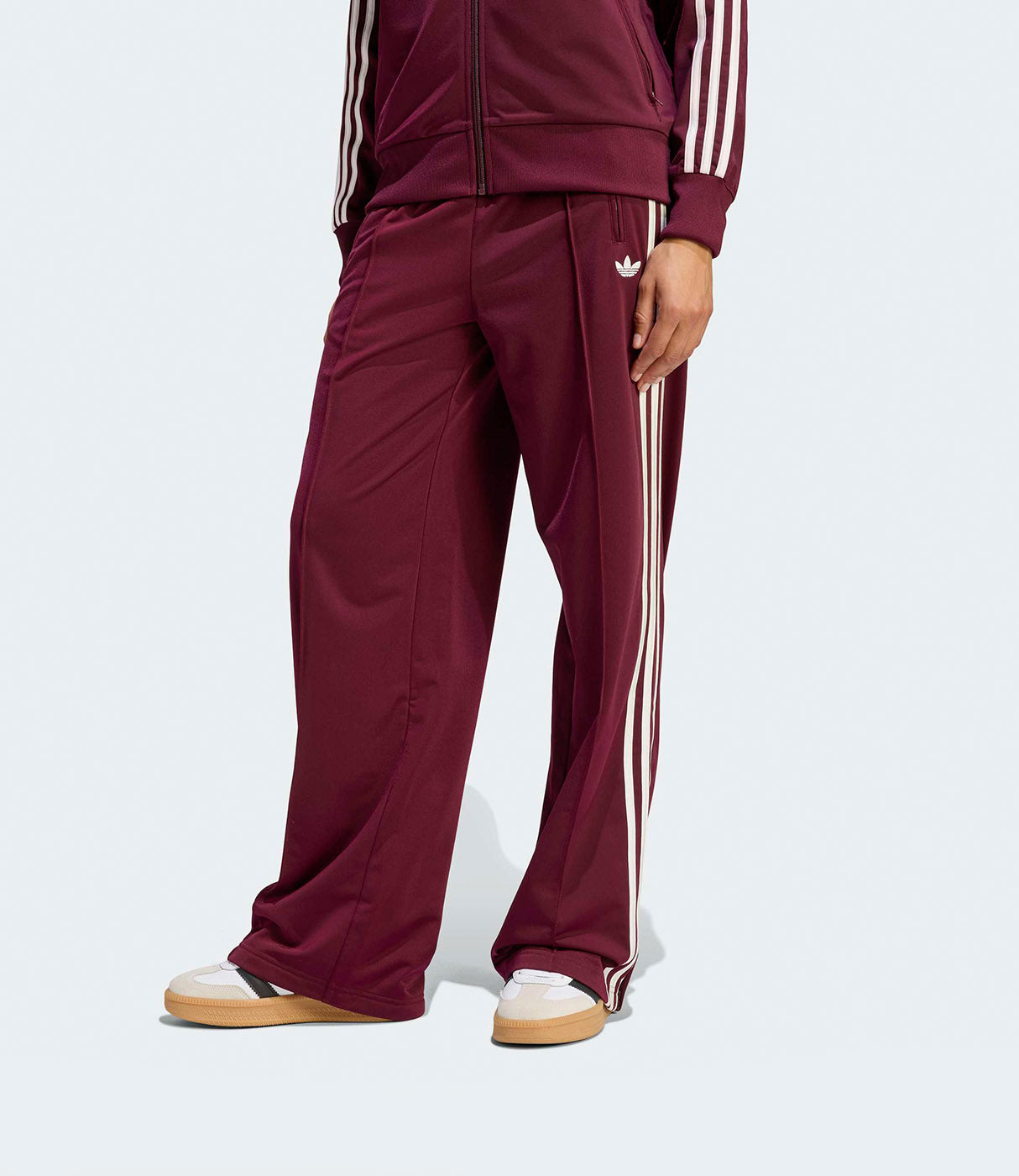 דגם עומד לובש חליפת טרנינג בורדו עם פסים לבנים ונעלי ספורט, צילום אופנה