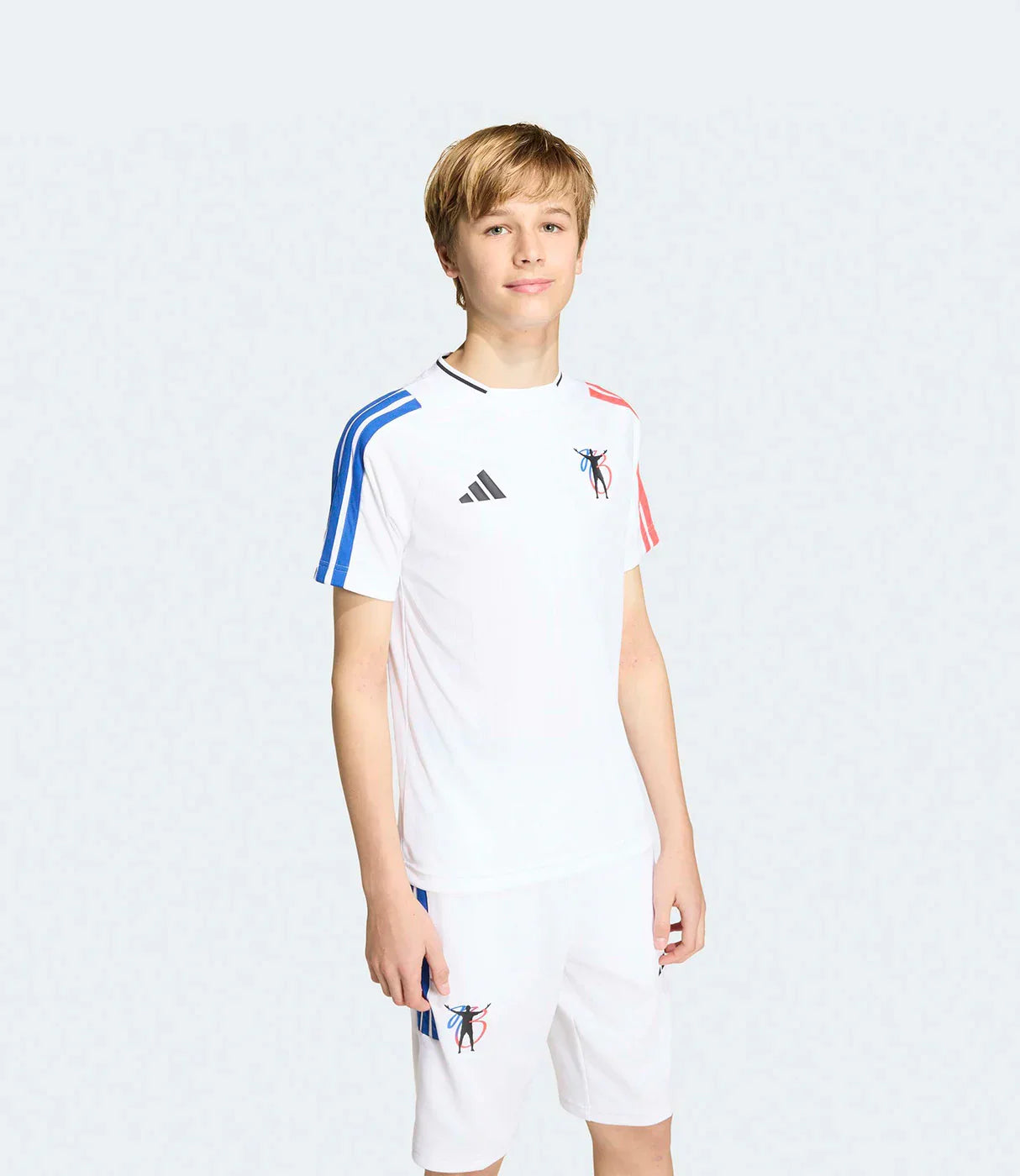 נער לובש סט ספורט לבן עם פסי שרוול כחול ואדום וסמל גרפי, בגדי ספורט אופנתיים