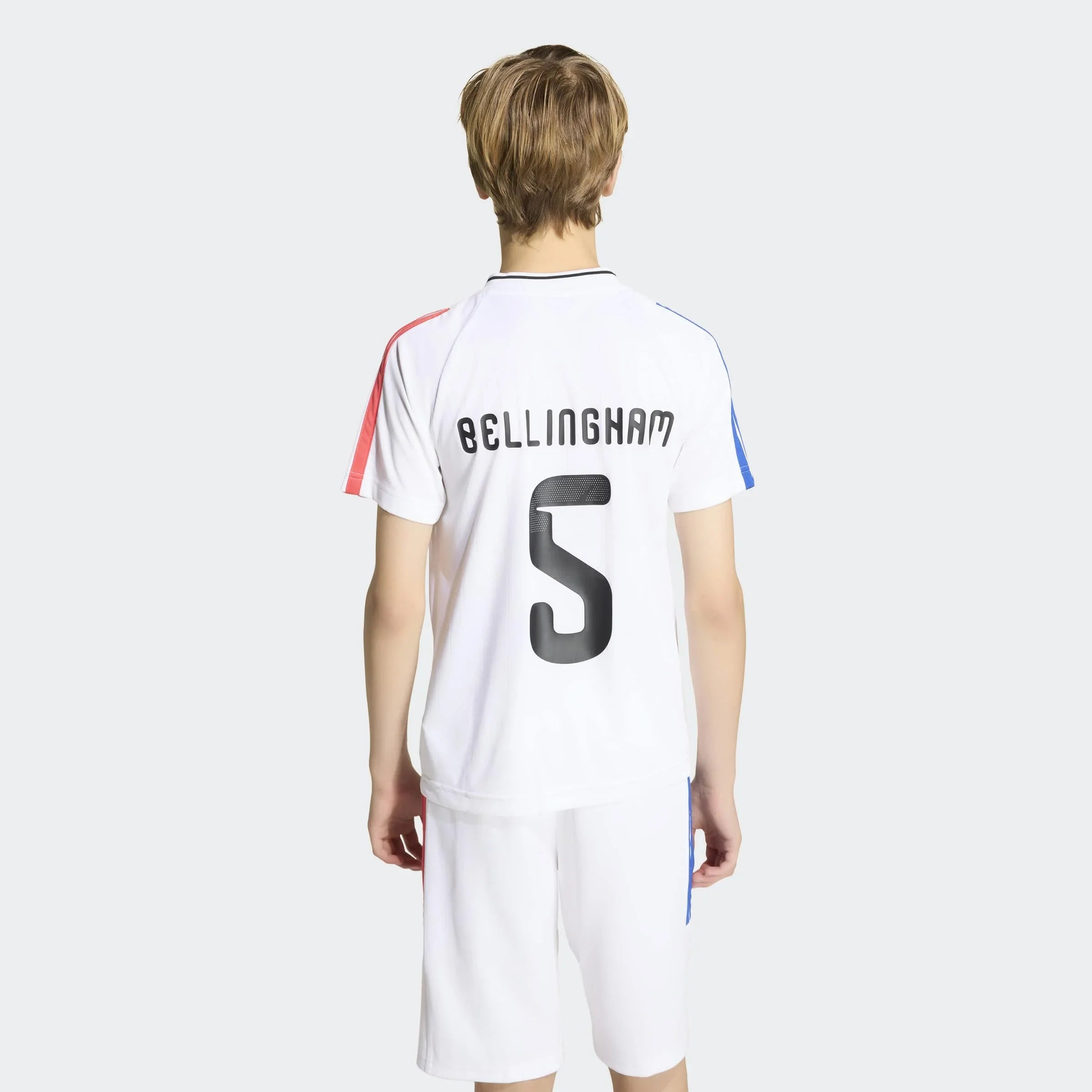 דגם לובש מדים לבנים עם שם ומספר "BELLINGHAM 5" בגב, מבט מאחור, רקע אפור
