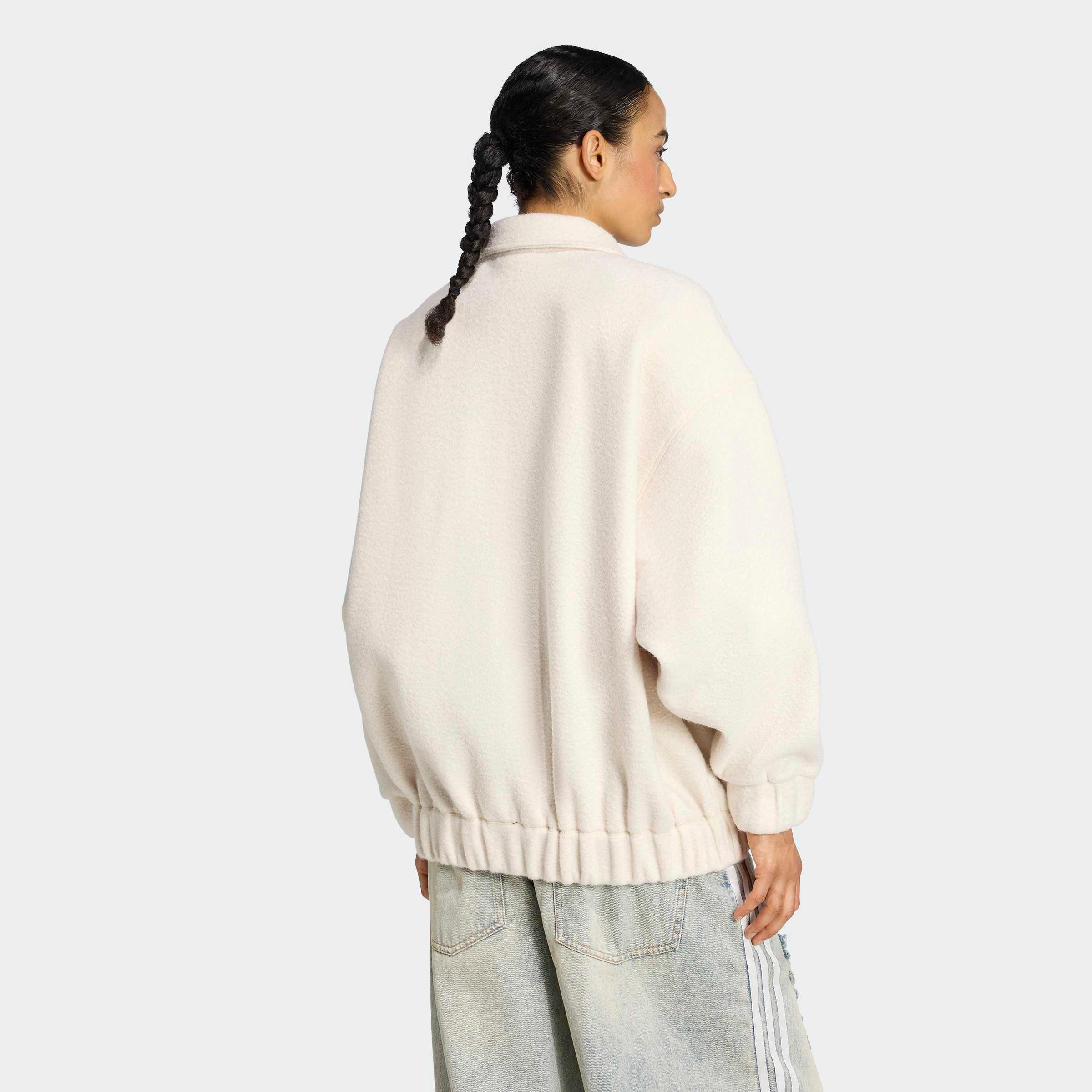 דוגמנית של CHOZEN בלוק גב, לובשת ג'קט פליס לבן ומכנסי ג'ינס רחבים