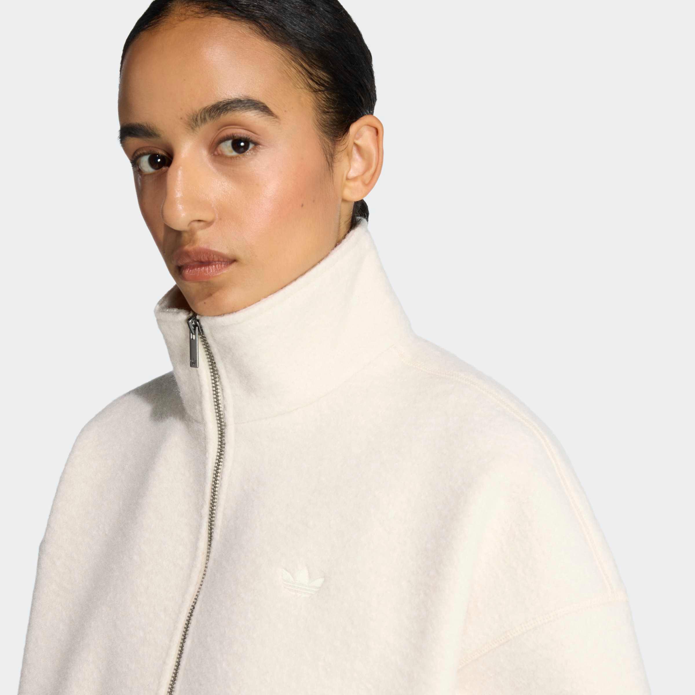 דוגמנית לובשת סווטשירט אדידס לבן עם רוכסן וסמל לוגו, אופנת CHOZEN