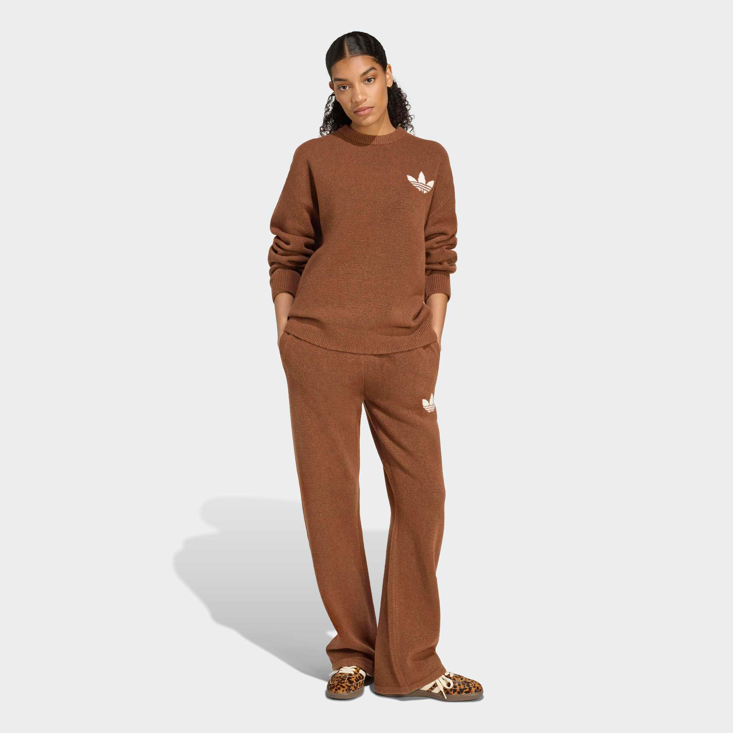 אישה לובשת סט טרנינג חום עם סמל אדידס, צילום אופנה רקע לבן, CHOZEN מותגים מובילים