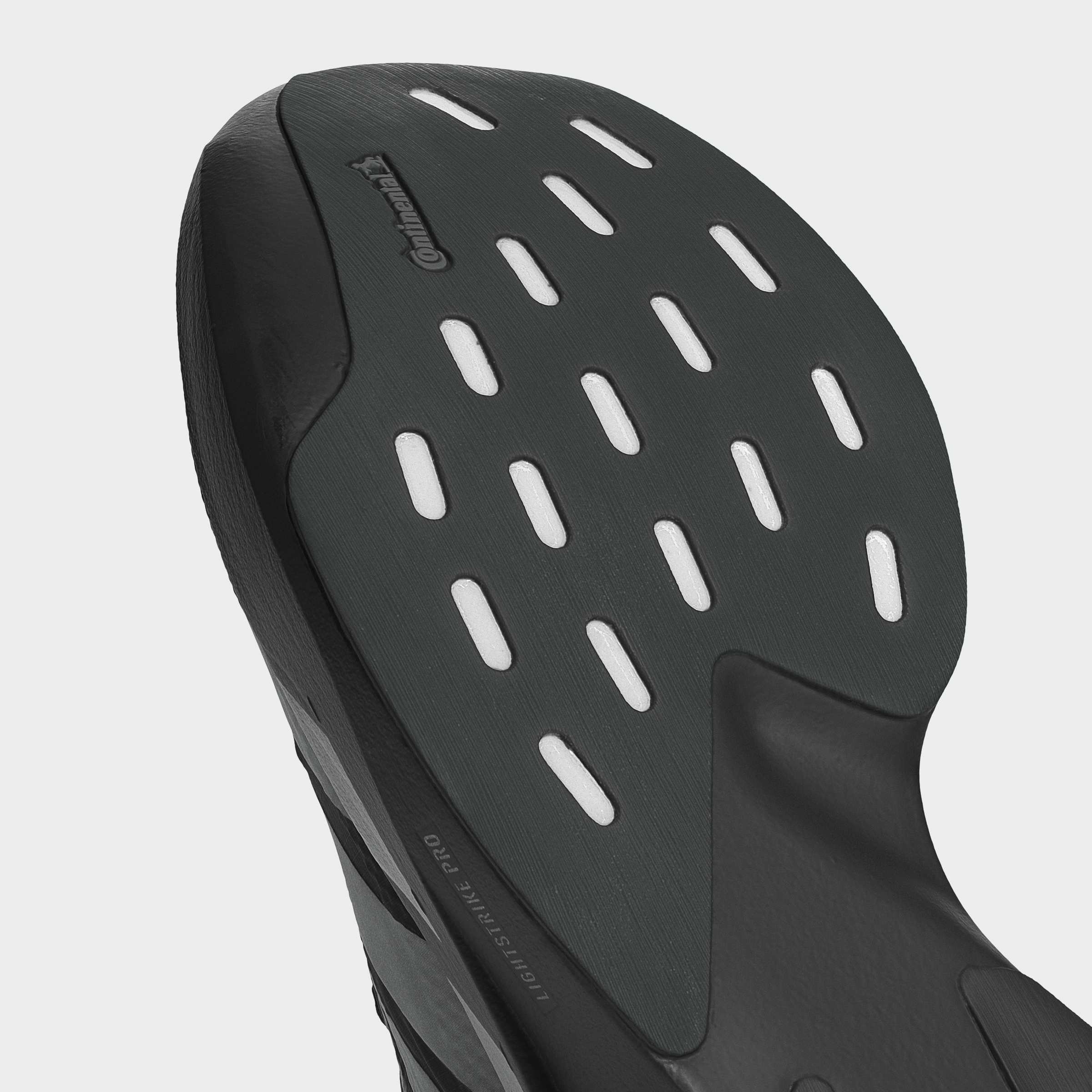 תקריב סוליית נעל ריצה בצבע שחור עם חריצים לבנים, טכנולוגיה מתקדמת לאחיזת כביש