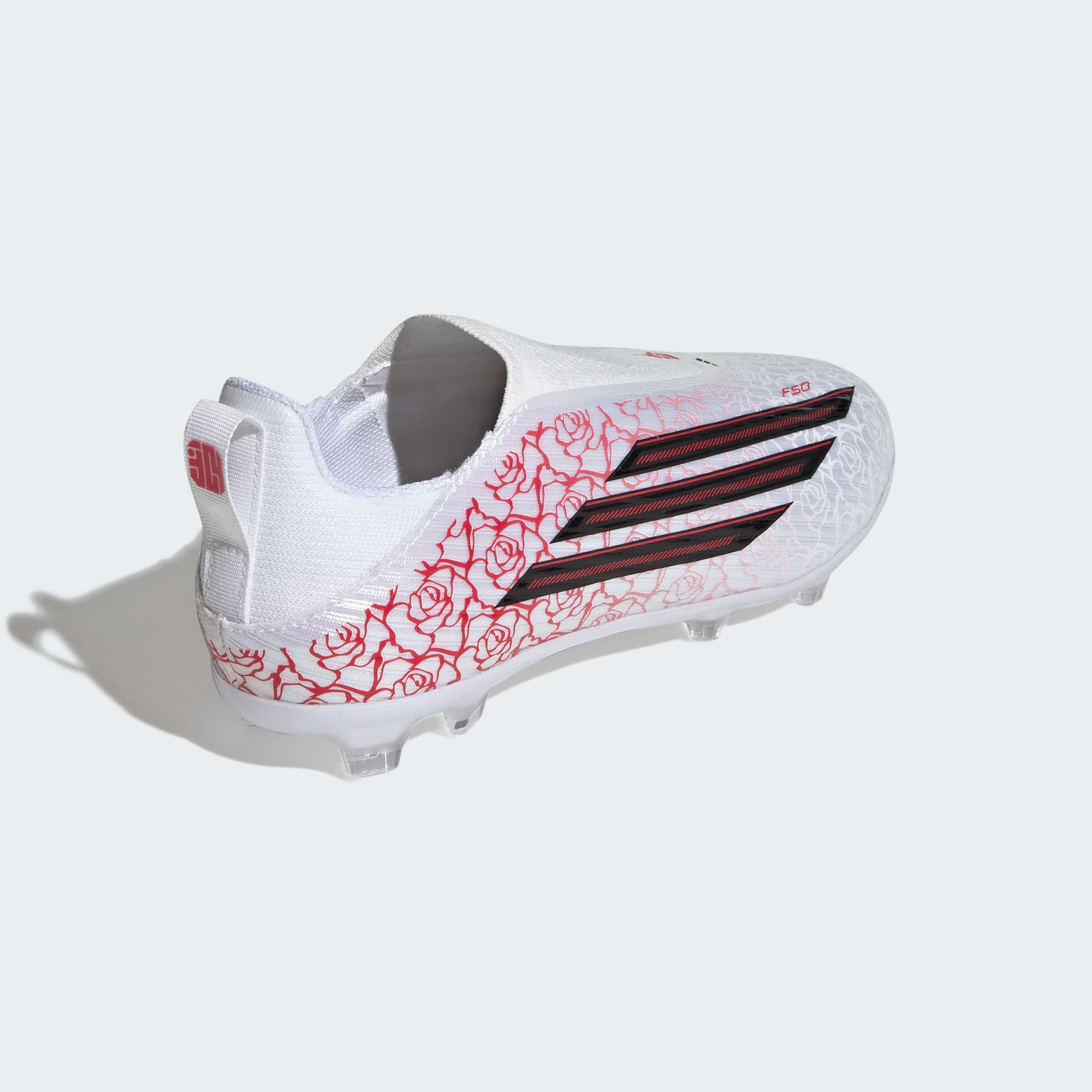 נעל כדורגל לבנה עם דוגמת ורדים אדומים וסוליה שקופה, מבט מהצד האחורי