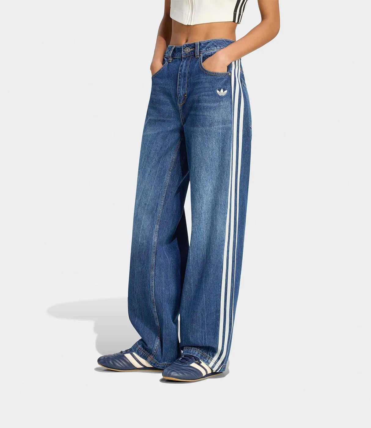 ג'ינס נשים גזרה רחבה עם פסי צד לבנים, חולצה קצרה ונעלי ספורט, צילום על רקע אפור