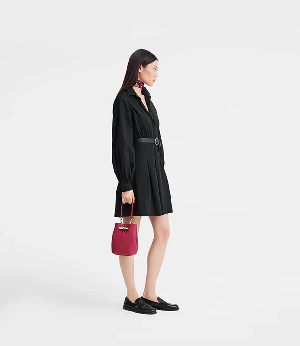 אישה בשמלה שחורה חגורה, אוחזת תיק אדום, אופנה עדכנית מבית CHOZEN
