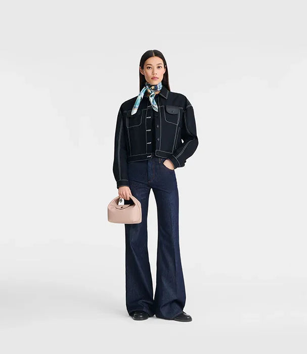 אישה עם ז'קט ג'ינס כהה, מכנס מתרחב וצעיף, מחזיקה תיק ורוד, אופנה CHOZEN