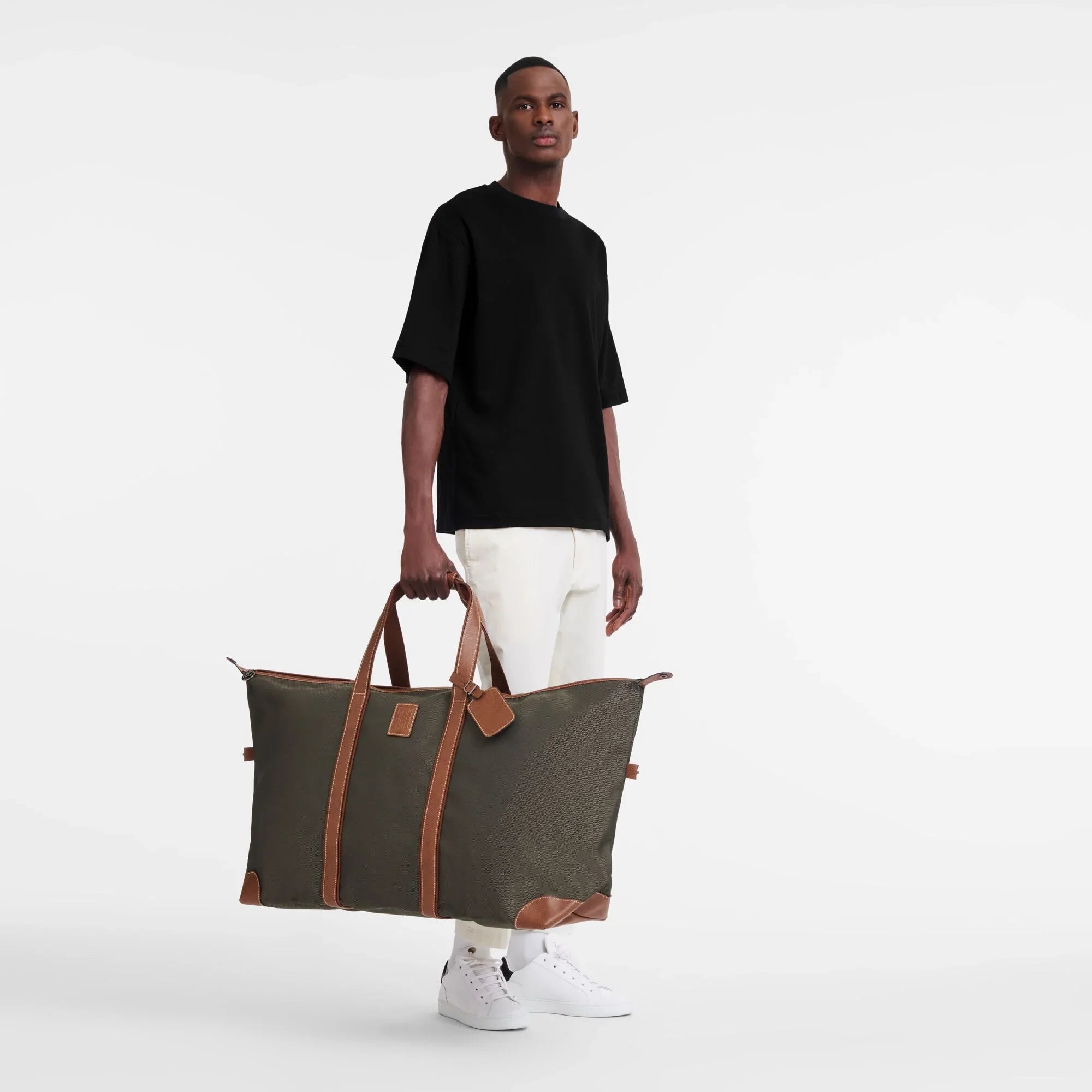 גבר עומד עם תיק נסיעות גדול ירוק עם רצועות עור, אופנה CHOZEN, רקע לבן