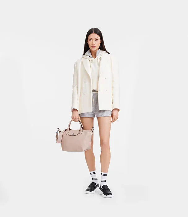 אופנת נשים CHOZEN, דוגמנית עם מעיל לבן, תיק בז', שורטס אפור ונעלי סניקרס לשיווק אלפא