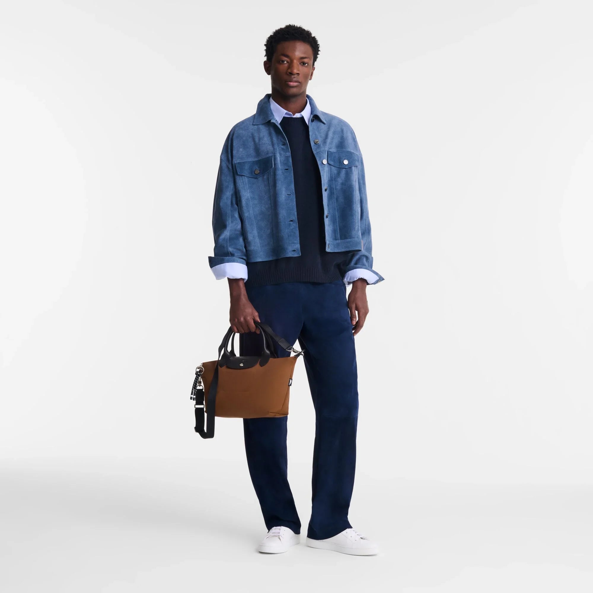 דוגמן לבוש בז'קט זמש כחול, חולצה מכופתרת ותיק חום, אופנת CHOZEN קבוצת אלפא