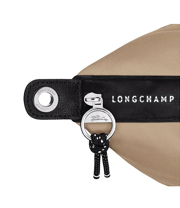 תקריב של רוכסן ותווית מותג LONGCHAMP על תיק בצבע בז', מוצר יוקרה מחנות CHOZEN