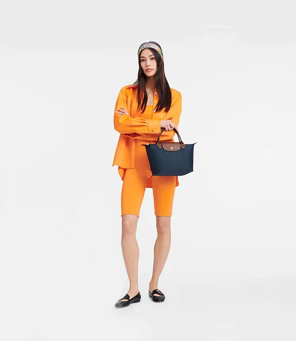אישה בלבוש כתום אופנתי מחזיקה תיק יד כחול, צילום קטלוג CHOZEN מותגים מובילים
