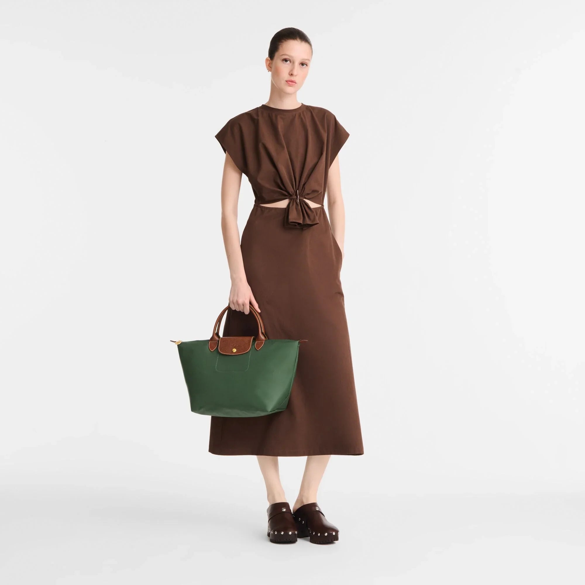 דוגמנית לובשת שמלת מקסי חומה ונושאת תיק ירוק, צילום קמפיין CHOZEN קבוצת אלפא