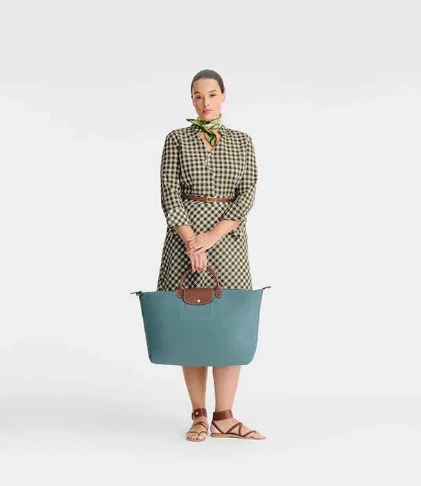 אישה בשמלת משבצות עם תיק יד גדול תכלת, אופנה יוקרתית ב-CHOZEN מבית קבוצת אלפא