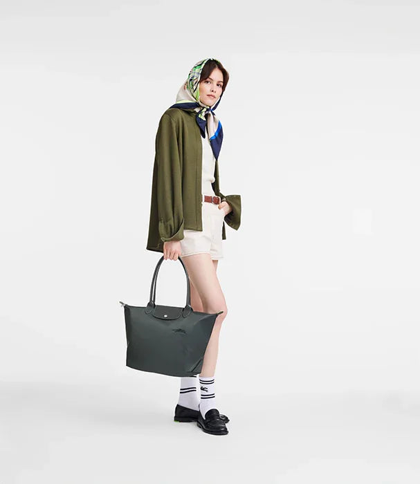 אשה עם מטפחת צבעונית, ז'קט ירוק, ותיק יד ירוק של מותג אופנה CHOZEN