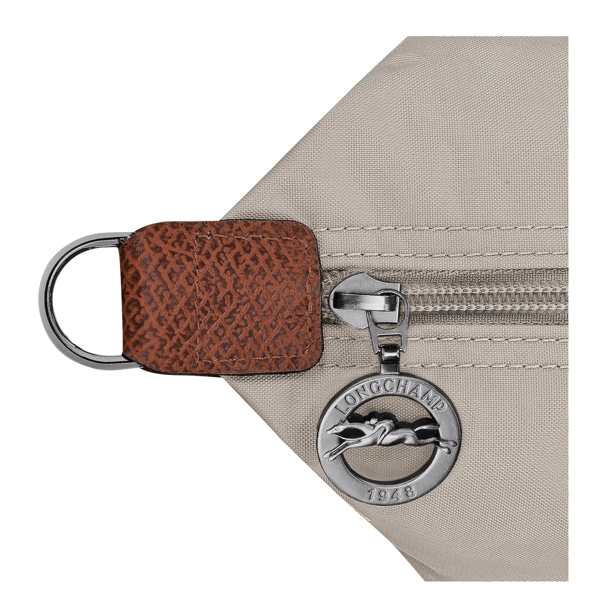 תקריב רוכסן תיק לונגשאמפ עם מחזיק עור חום וסמל לוגו מתכתי בעיצוב יוקרתי