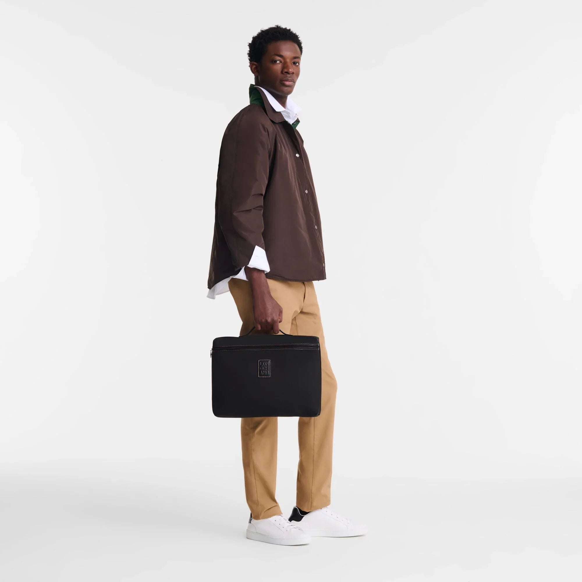 דוגמן מחזיק תיק עסקים שחור, לבוש חולצה חומה ומכנסי בז', CHOZEN מותגים מובילים