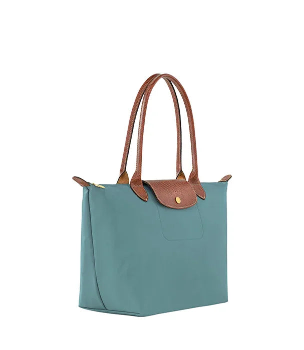 תיק נשי אופנתי בצבע טורקיז עם ידיות וחלק עליון דמוי עור חום, מוצג על רקע לבן, CHOZEN