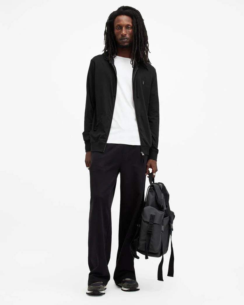 דוגמן לובש ג'קט שחור, חולצה לבנה ומחזיק תיק גב, אופנה עדכנית מבית CHOZEN