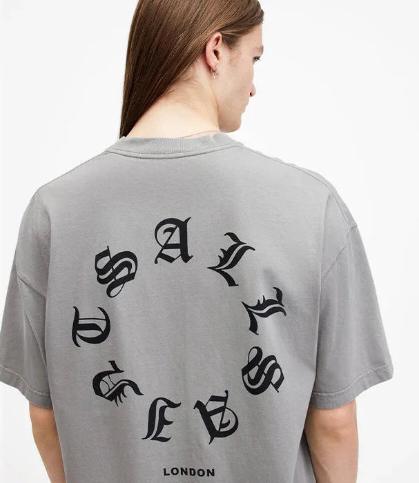 אדם לובש חולצת טי שרט אפורה עם כיתוב שחור עגול בגב, מותג STREETWEAR מבית CHOZEN