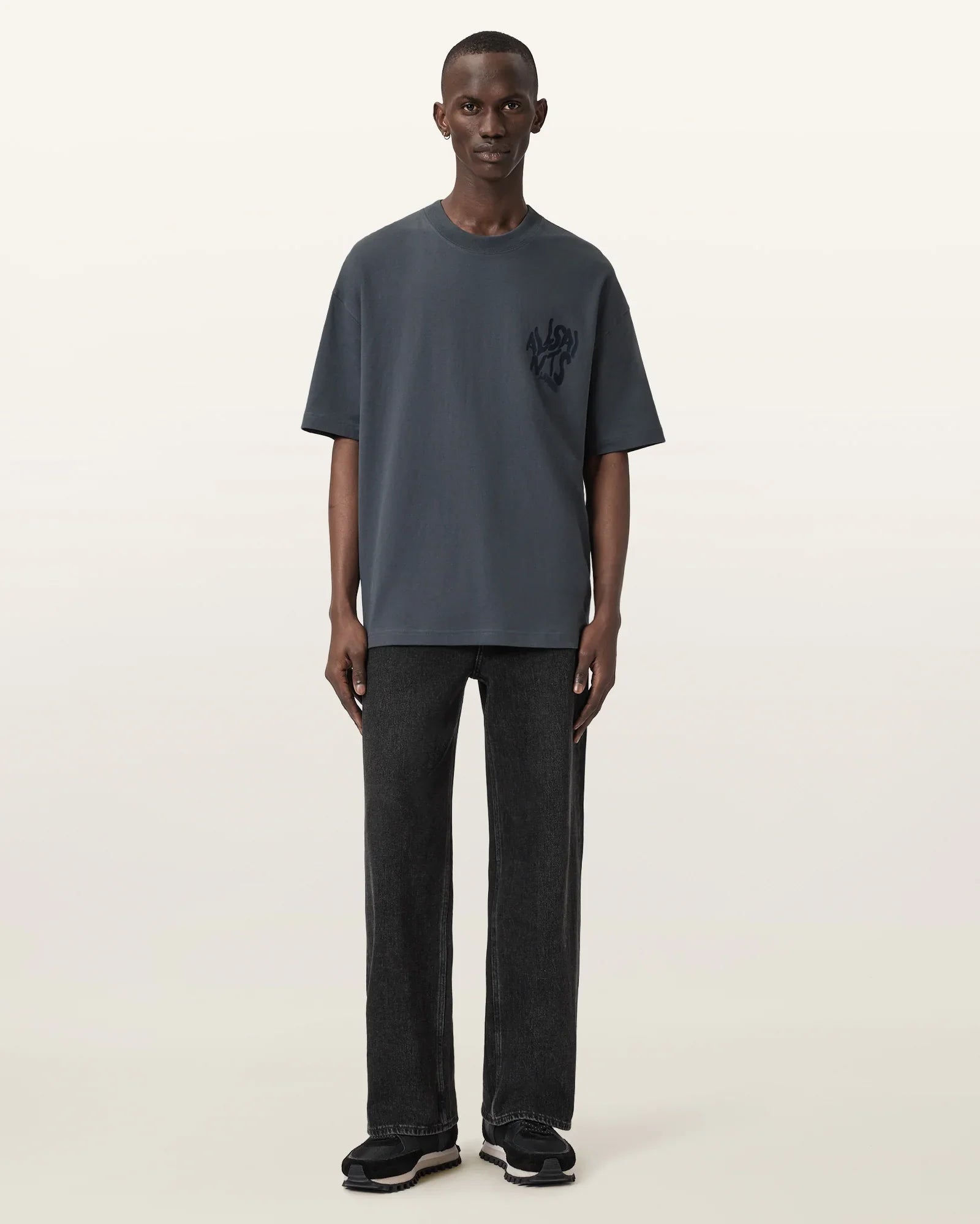 גבר לובש חולצת טי כהה עם לוגו CHOZEN ומכנסי ג'ינס שחורים, צילום לאופנת רחוב יוקרתית