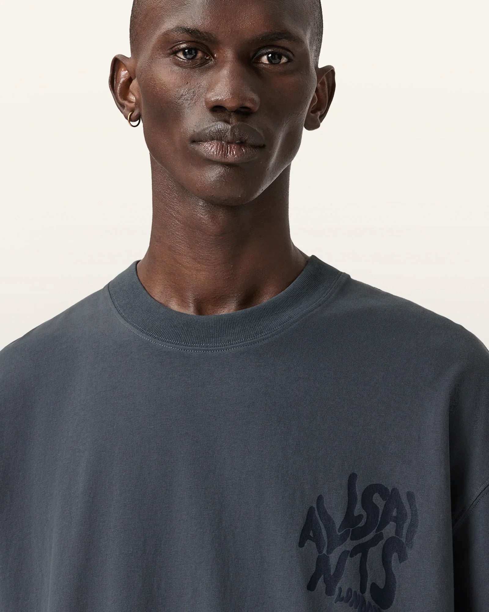 גבר לובש חולצת בייסיק כהה עם לוגו ALLSAINTS, צילום אופנה באתר CHOZEN