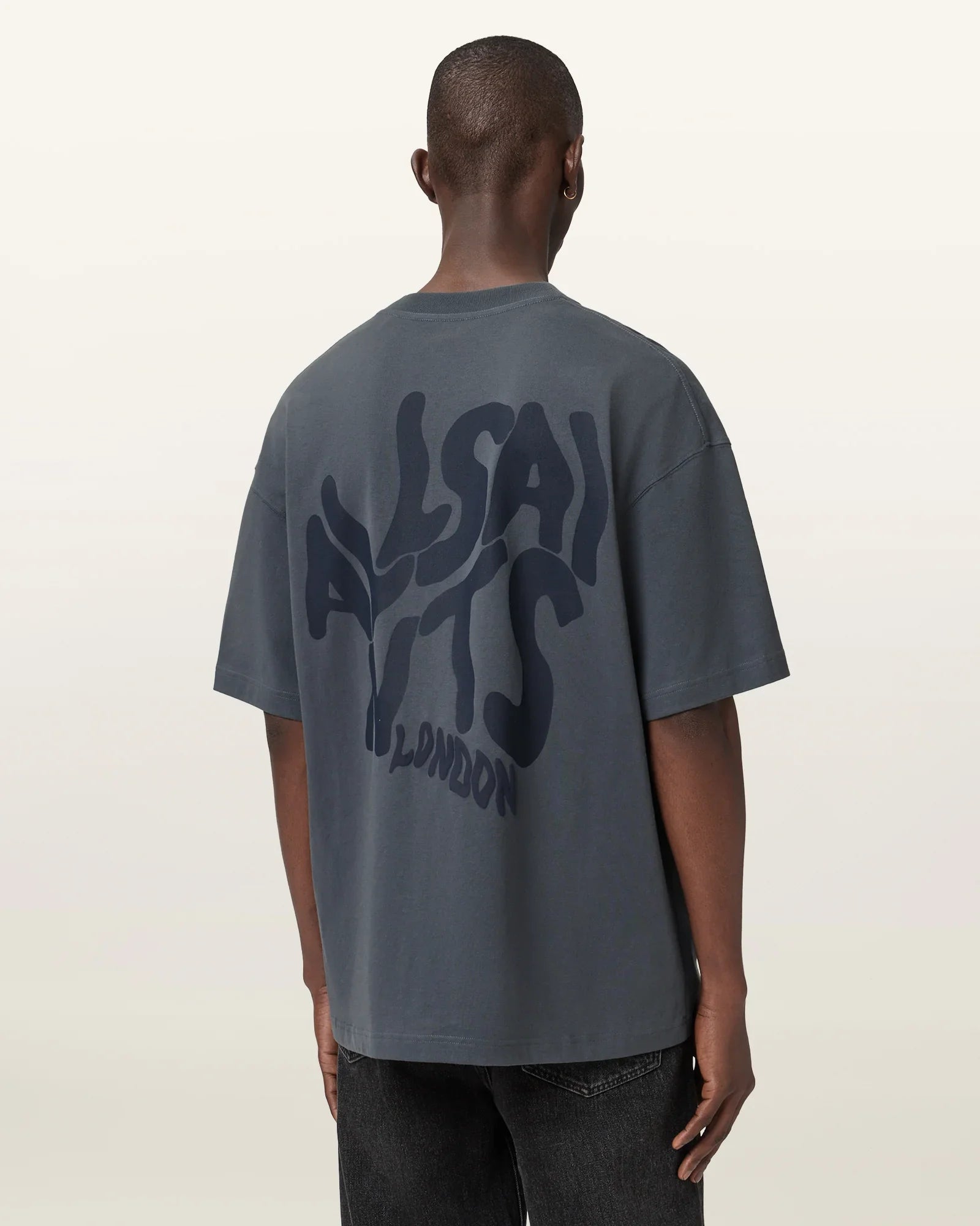 גבר לובש חולצת טי אפורה עם הדפס ALLSAINTS LONDON בגב, אופנה ממותגי CHOZEN