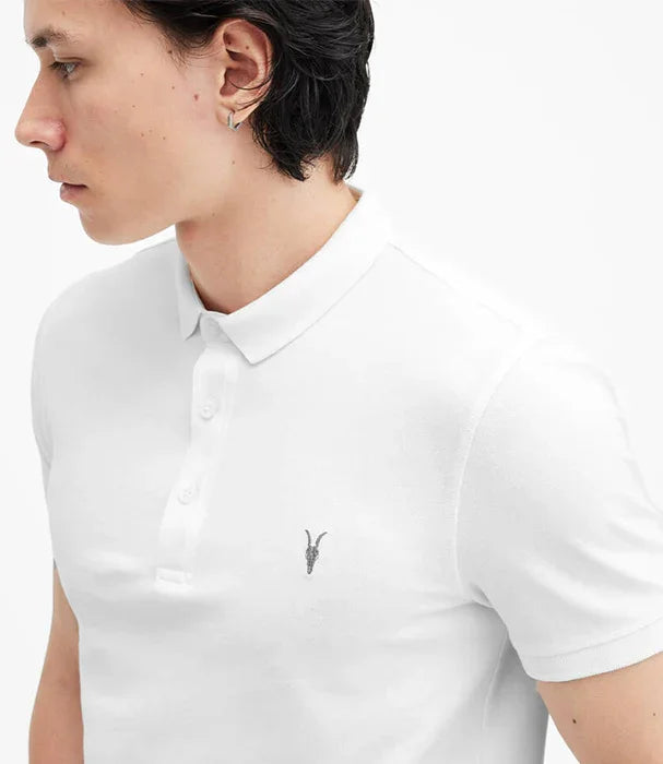 דוגמן לובש חולצת פולו לבנה ממותגת CHOZEN עם רקמה של עופר בחזה