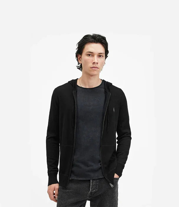 גבר צעיר לובש קפוצ׳ון שחור אופנתי של CHOZEN, רקע לבן, אופנת גברים מודרנית