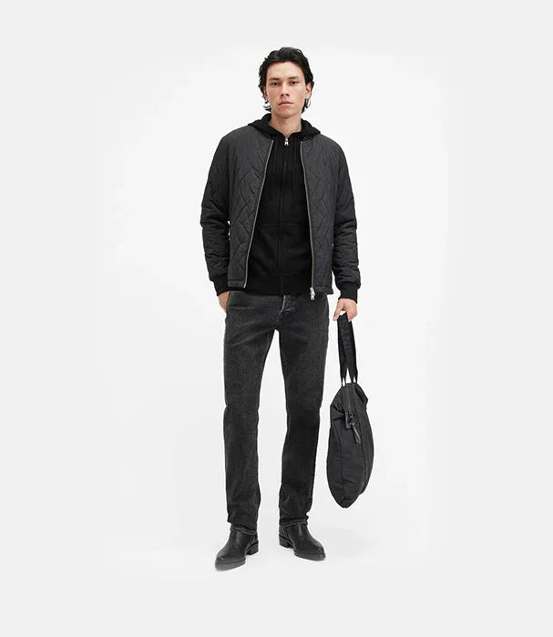 גבר לובש מעיל שחור, ג'ינס כהה ומחזיק תיק שחור, אופנת גברים CHOZEN