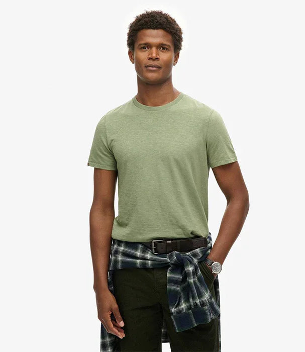 גבר לובש חולצת טי ירוקה של CHOZEN, חולצה משובצת קשורה במותניים, עומד על רקע לבן