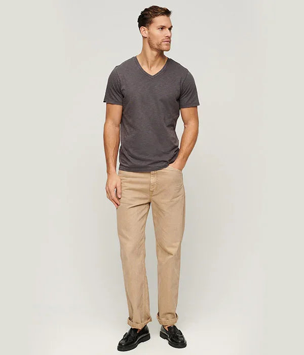 גבר דוגמן של CHOZEN לובש חולצה אפורה ומכנסיים בז', צולם על רקע לבן