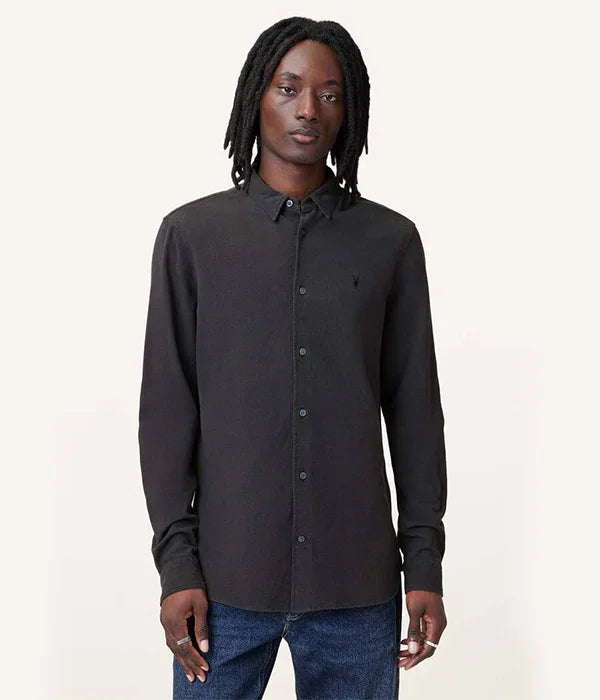 גבר לובש חולצה שחורה מכופתרת מבית CHOZEN קבוצת אלפא על רקע בהיר