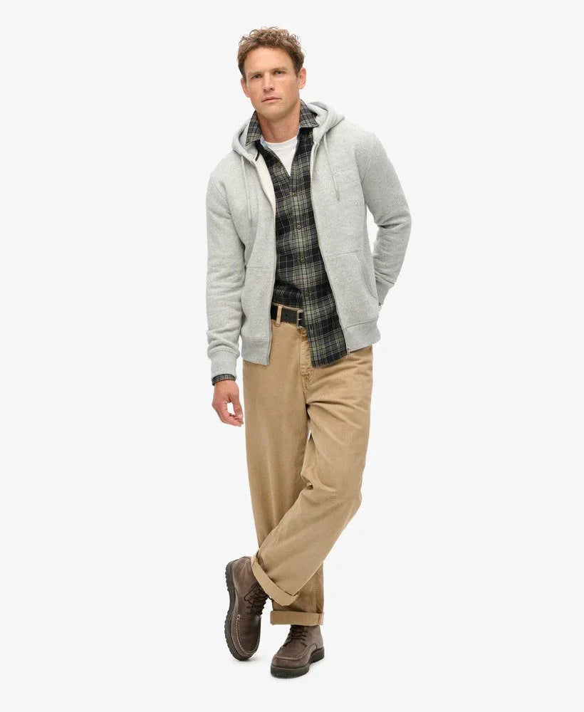 גבר מדגמן סווטשירט אפור, חולצה משובצת ומכנס בז' מבית CHOZEN על רקע לבן