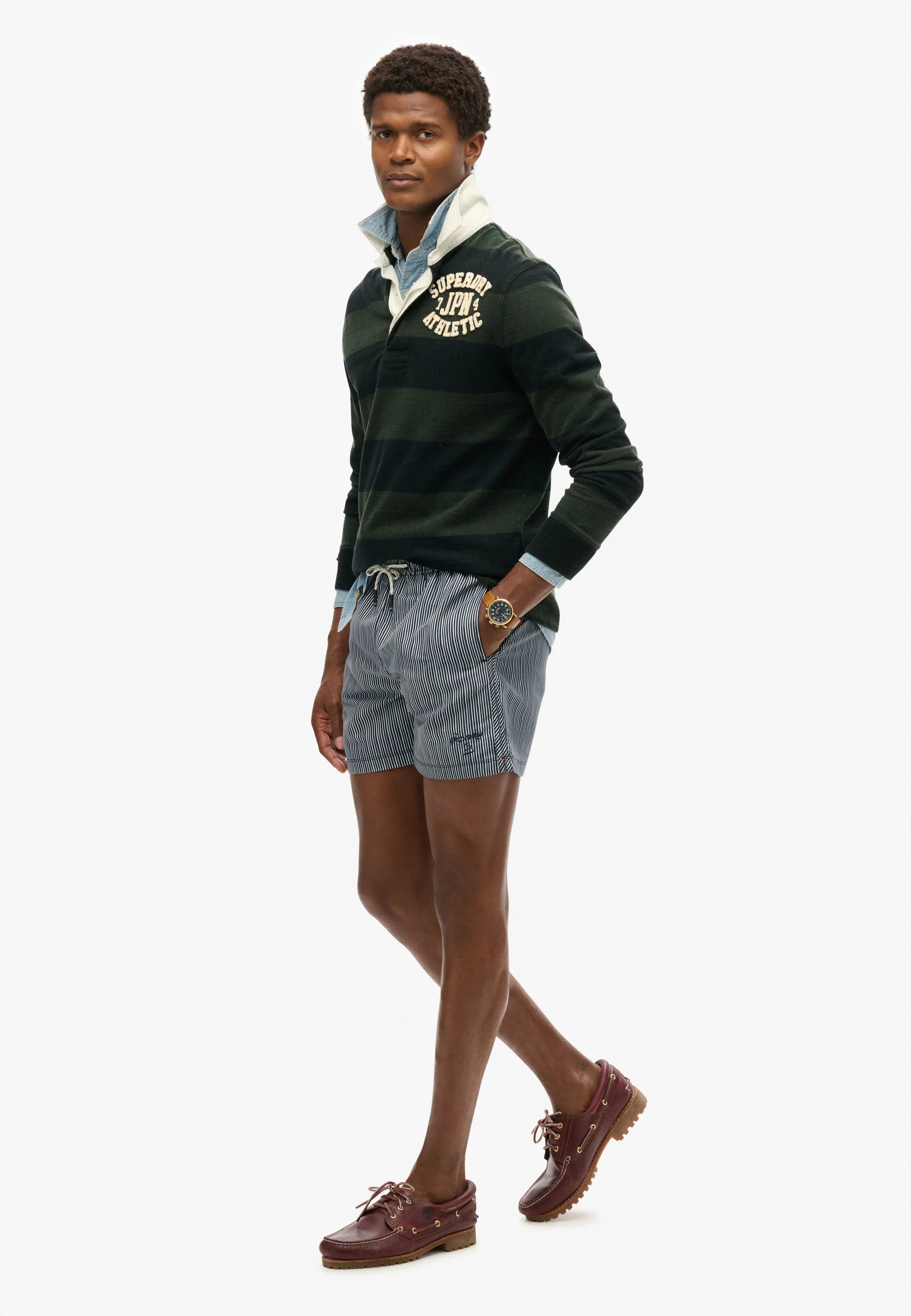 דוגמן לובש סווטשירט ירוק עם כיתוב SUPERDRY, מכנס קצר פסים ונעלי מוקסין, אופנת גברים CHOZEN