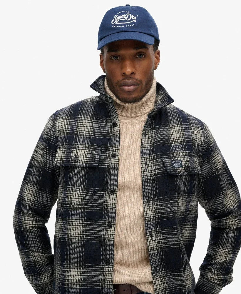 דגם גבר בכובע כחול של Superdry, חולצת פלנל משובצת, וסוודר בז', מבית קבוצת אלפא CHOZEN