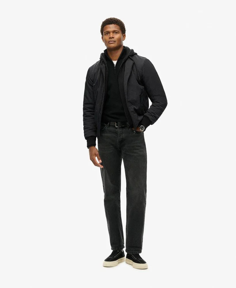 דגם גבר לובש מעיל שחור, ג'ינס כהה ונעליים כהות, אופנה עדכנית ב-CHOZEN