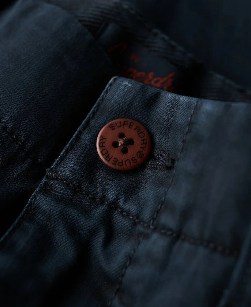 כפתור חום עם כיתוב SUPERDRY על מכנס ג'ינס כהה, מותג אופנה מוביל ב-CHOZEN