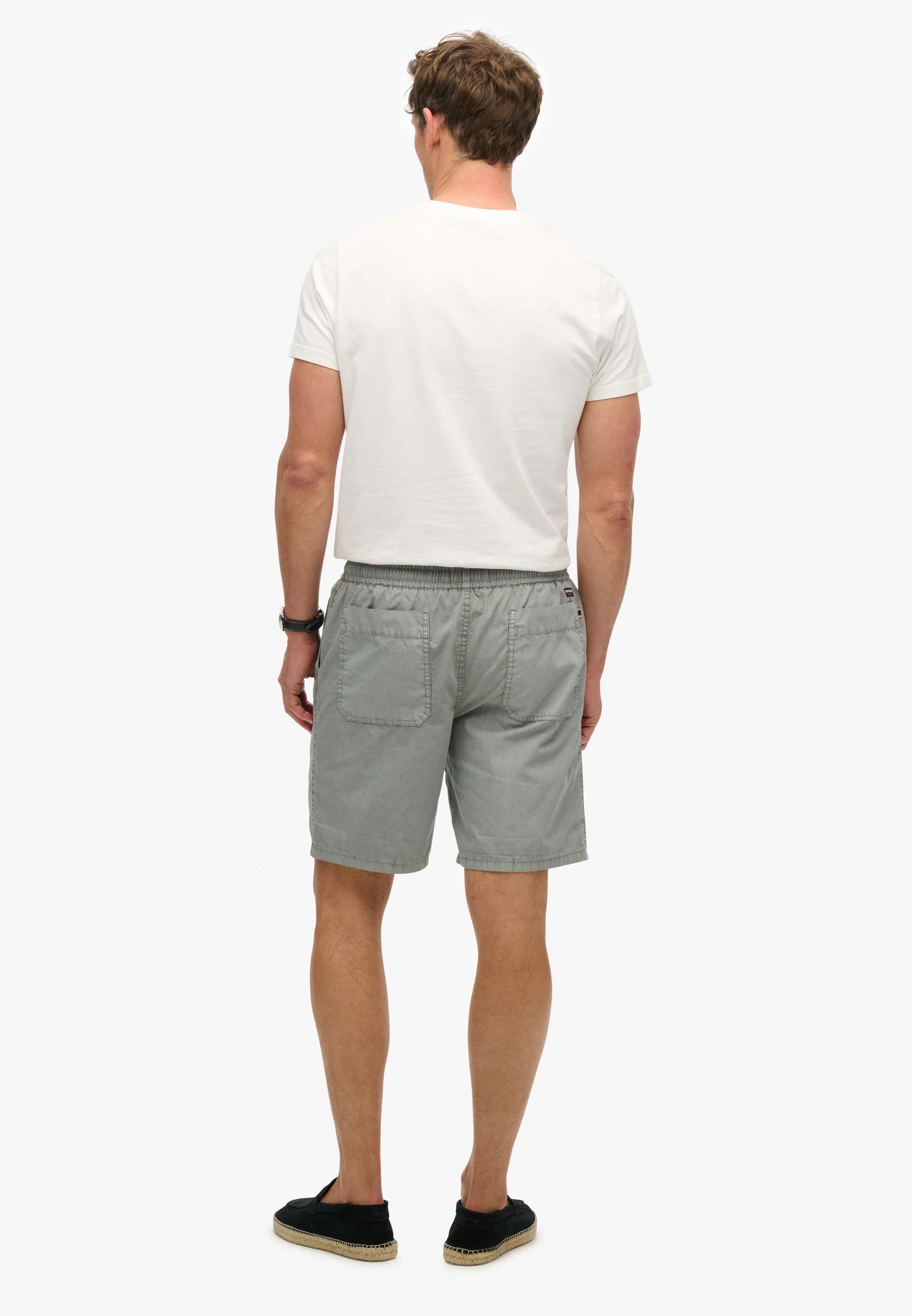 גבר בחולצה לבנה ומכנסיים קצרים אפורים, קולקציית קיץ CHOZEN, צילום אחורי, בגדי מותגים