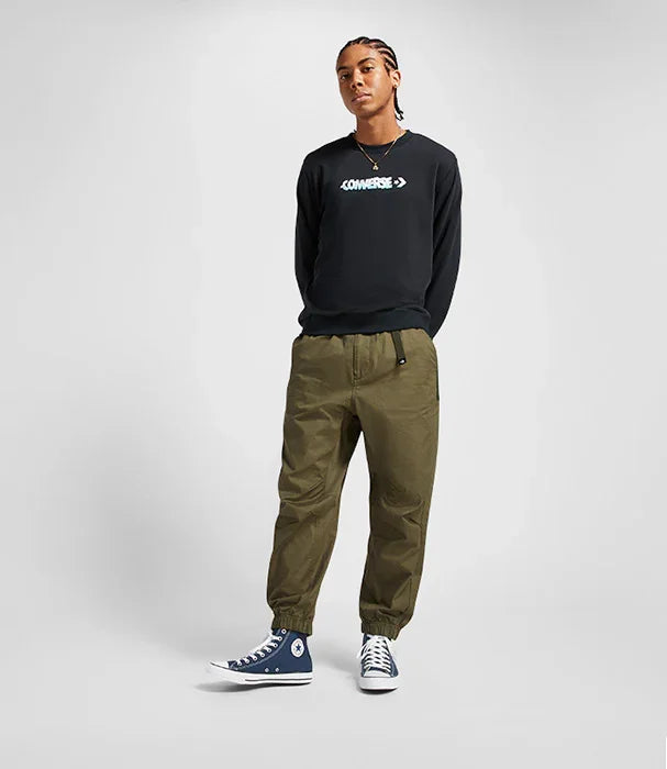 דוגמן לובש סווטשירט שחור של קונברס, מכנסיים ירוקים ונעלי אולסטאר כחולות. CHOZEN מותגים מובילים.