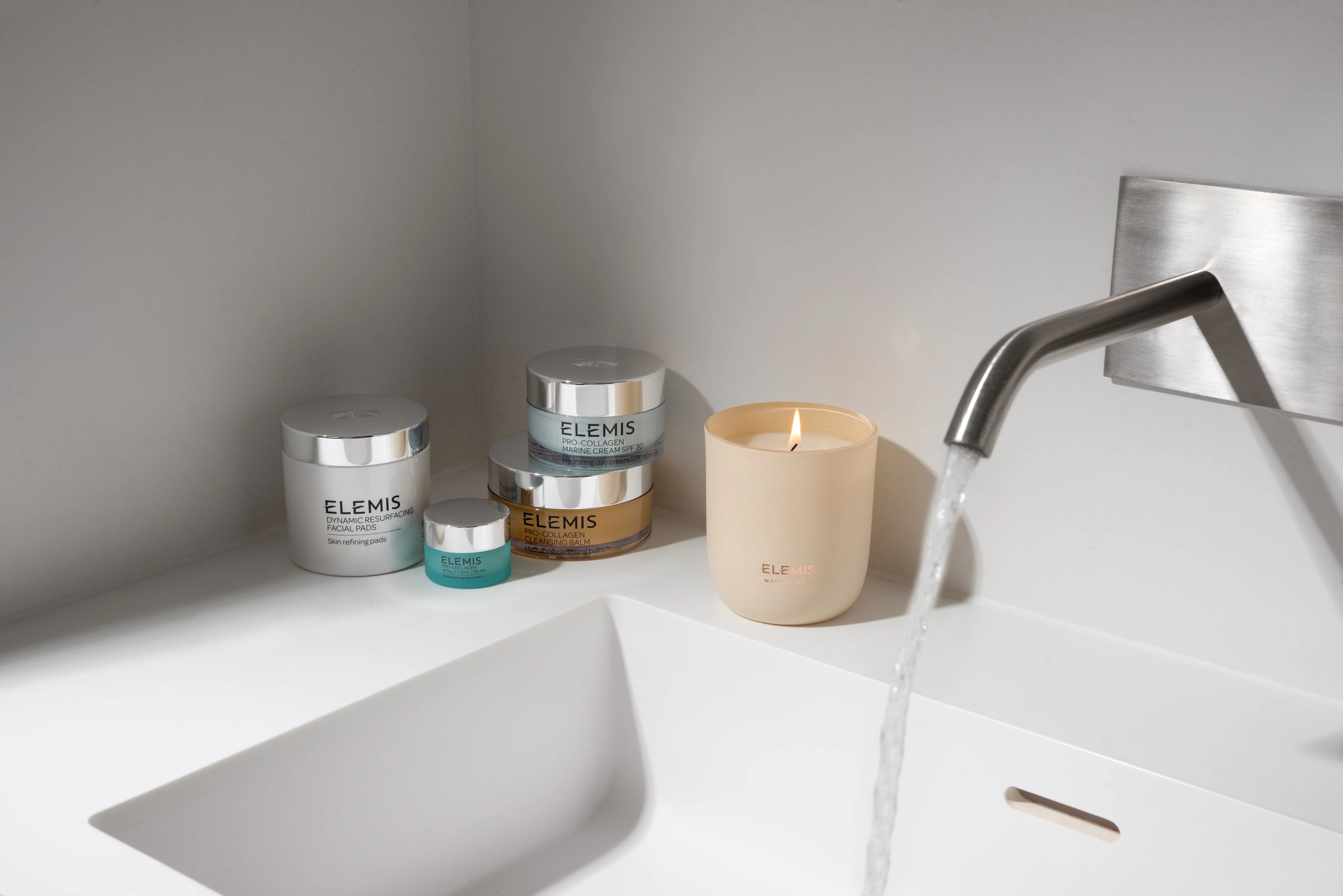 מוצרי טיפוח וספא ELEMIS לצד נר דולק בכיור מודרני, מותגים בינלאומיים CHOZEN