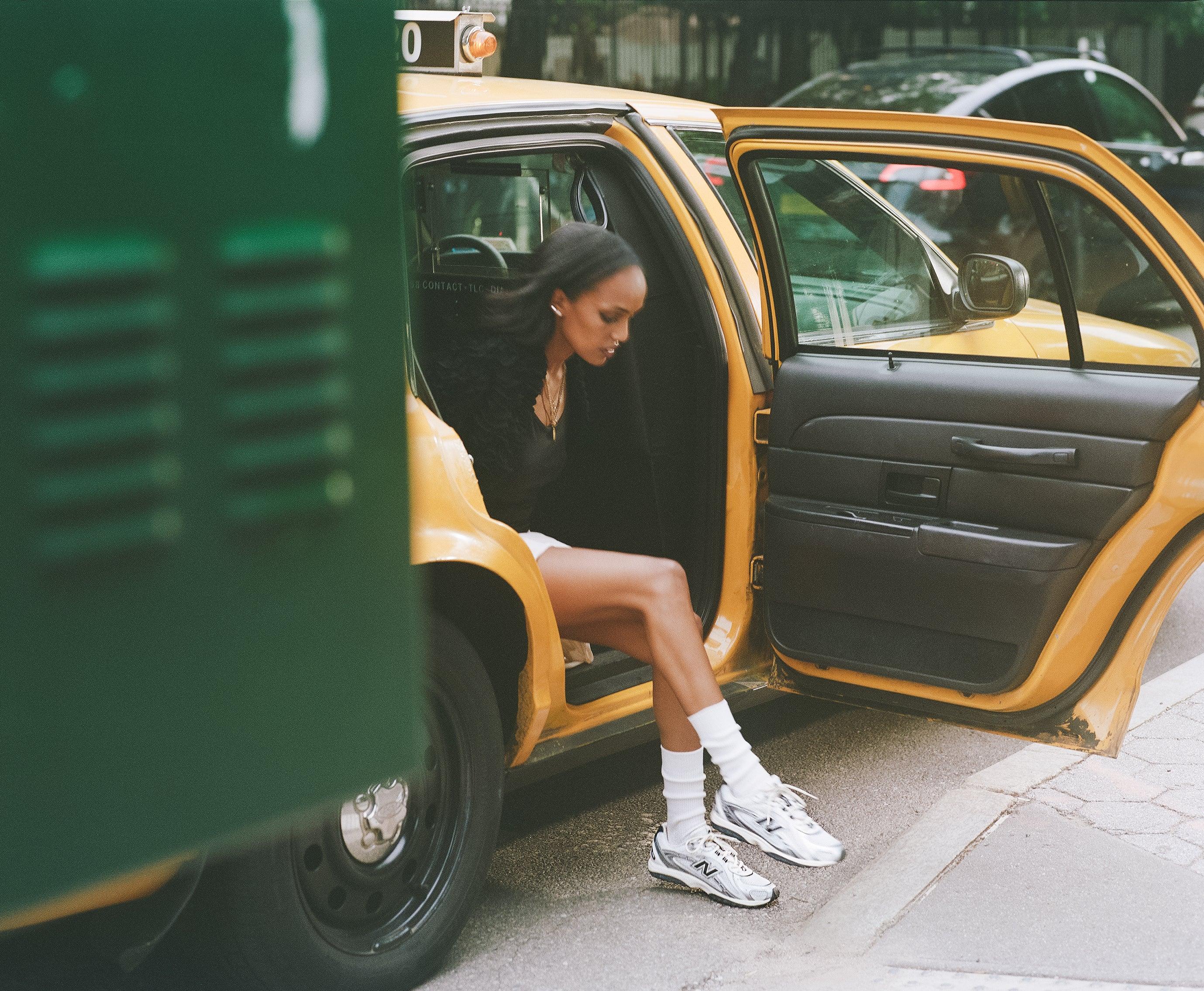 אישה אלגנטית בנעלי ניו באלאנס יוצאת ממונית צהובה, אופנה אורבנית CHOZEN