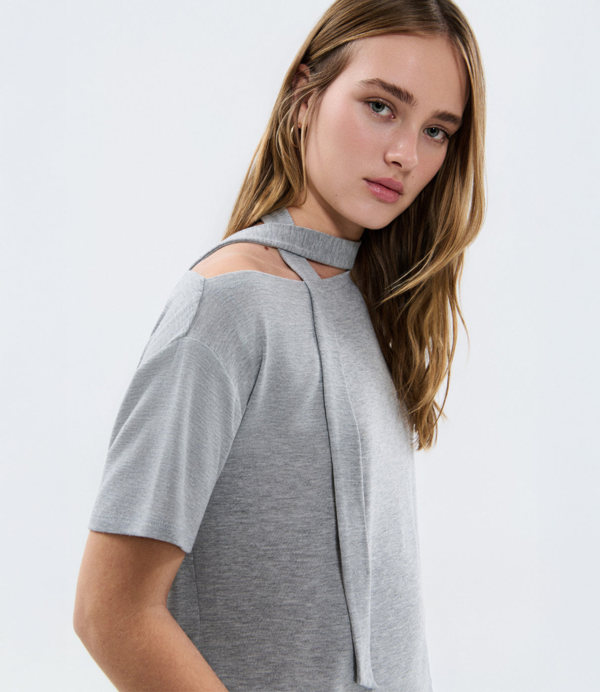 אישה לובשת חולצת טריקו אפורה עם גזרה מודרנית וכתפיים חשופות