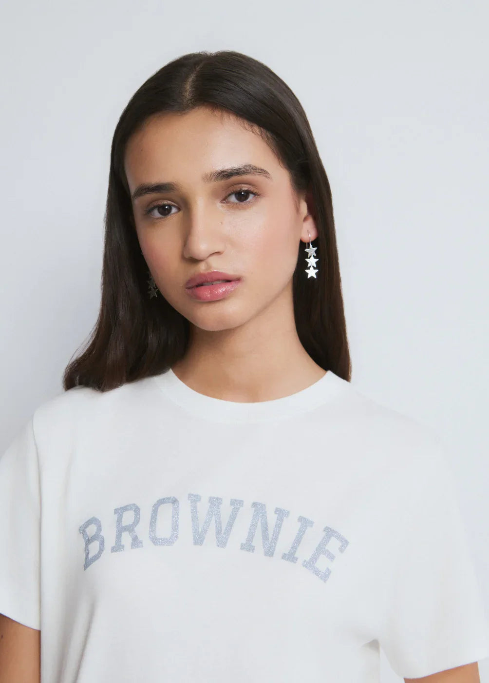 דוגמנית עם חולצה לבנה עם כיתוב BROWNIE ועגילי כוכבים, אופנה טרנדית ב-CHOZEN