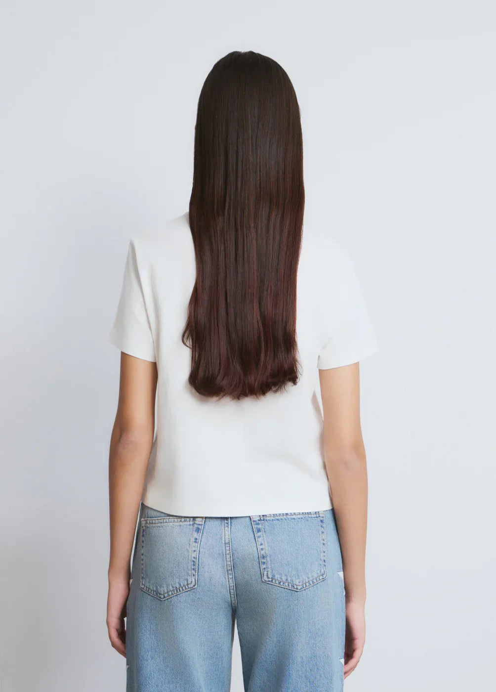 אישה עם שיער חום ארוך לובשת חולצה לבנה וג'ינס כחול, צילום מאחור, CHOZEN מותגים מובילים