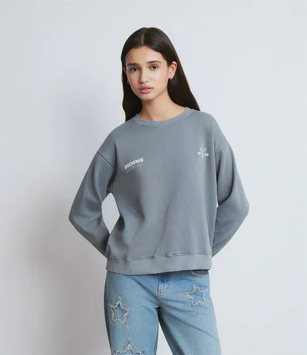 דוגמנית לובשת סווטשירט אפור עם כיתוב BROWNIE ומכנסי ג'ינס עם כוכבים, CHOZEN מותגים מובילים