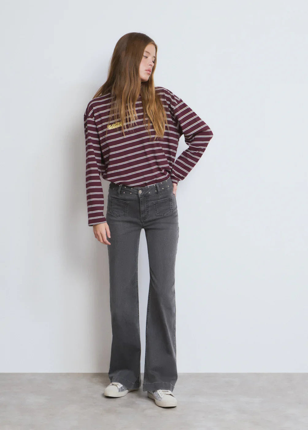 דוגמנית לובשת חולצת פסים בורדו ומכנסי ג'ינס אפורים, אופנת נשים CHOZEN